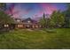 Expansive backyard of this brown home features a large lawn and patio with outdoor seating at 8576 Niwot Meadow Farm Rd, Niwot, CO 80503