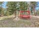 Tranquil backyard scene with a charming wooden swing set nestled among the trees, perfect for relaxation at 8795 Rudd Rd, Evergreen, CO 80439