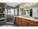 Modern bathroom featuring double sinks, a glass-enclosed shower with gray tile, and open shelving at 600 N 15Th Ave, Brighton, CO 80601