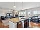 Open-concept kitchen with eat-in island flowing into a cozy living room featuring a fireplace and a dining area at 6019 S Little River Way, Aurora, CO 80016