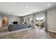 Open living room featuring a grey sectional sofa, hardwood-style flooring, and a sliding door leading to the patio at 6019 S Little River Way, Aurora, CO 80016