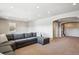 Comfortable living room with a grey sectional sofa, carpeted floors, and an archway leading to another room at 6019 S Little River Way, Aurora, CO 80016