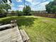 Large backyard with green grass, a wooden fence, landscaping, and a wooden deck with bench at 7431 Webster St, Arvada, CO 80003