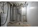 Utility room featuring the water heater, pipes and a grey electrical box on the concrete wall at 7431 Webster St, Arvada, CO 80003