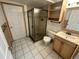 Bathroom with a tiled floor, shower stall, vanity with sink, and wooden shelves above toilet at 7431 Webster St, Arvada, CO 80003