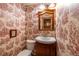 A quaint powder room boasts a charming vanity, toilet, and unique toile wallpaper at 7431 Webster St, Arvada, CO 80003