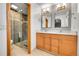 Modern bathroom showcasing a double sink vanity, tiled floors, and a glass enclosed shower at 12287 W Aqueduct Dr, Littleton, CO 80127