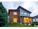 Modern two-story home featuring a combination of wood, stone, and gray siding with inviting front porch lighting at 4251 Perry St, Denver, CO 80212