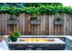 Stone fire pit surrounded by lush greenery and a wooden fence decorated with flower boxes at 4251 Perry St, Denver, CO 80212