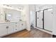 Bathroom with double sink vanity, glass shower, and wood-look flooring at 1255 Penner Dr, Erie, CO 80026