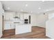 Clean kitchen features white cabinets, stainless steel hood, quartz counters, and a center island with a sink at 1255 Penner Dr, Erie, CO 80026