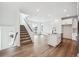 Open-concept kitchen with hardwood flooring, stainless steel appliances, white cabinetry and adjacent staircase at 1255 Penner Dr, Erie, CO 80026