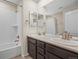 Bathroom featuring double sinks, a tub/shower combo with white tiling, and bronze hardware at 844 Dakota Ln, Erie, CO 80516