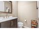 Modern powder room featuring a dark wood vanity, elegant mirror, and a convenient toilet at 844 Dakota Ln, Erie, CO 80516