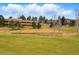 Picturesque view of a golf course with a pond and geese, framed by trees and a building in the distance at 7831 Inverness Blvd, Englewood, CO 80112