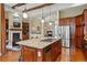 Open kitchen featuring a large island with a cooktop, stainless steel appliances, and wood cabinetry at 7831 Inverness Blvd, Englewood, CO 80112