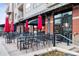 Charming patio seating at a restaurant with red umbrellas and tables with black chairs at 7831 Inverness Blvd, Englewood, CO 80112