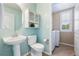 Well-lit powder room with pedestal sink, toilet, and adjacent laundry room with washer at 10978 Ashurst Ln, Highlands Ranch, CO 80130