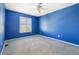 Blue bedroom featuring plush carpet, ceiling fan, and bright natural light through a shuttered window at 10978 Ashurst Ln, Highlands Ranch, CO 80130