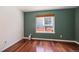 Cozy bedroom featuring hardwood floors, green accent wall and a window with backyard views at 17045 Hastings Ave, Parker, CO 80134