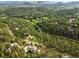 Aerial view of the house nestled in a beautiful, lush green forest with winding roads and a peaceful, secluded setting at 2548 Keystone Dr, Evergreen, CO 80439