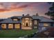 Stunning luxury home with a stone and stucco exterior, tile roof, and lush green lawn at sunset at 2548 Keystone Dr, Evergreen, CO 80439