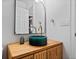 Modern bathroom with a unique green vessel sink, wood vanity, and arched mirror at 7633 S Gilpin Ct, Centennial, CO 80122