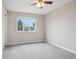 A bright, carpeted bedroom with a ceiling fan and view of a tree-lined street at 4623 S Kalispell Way, Aurora, CO 80015