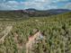 Panoramic aerial view of a mountain home surrounded by tall pine trees with picturesque hills in the distance at 31932 Steven Way, Conifer, CO 80433