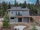 Contemporary home featuring a spacious deck, gray siding, a walkout basement, and surrounded by a lush forest setting at 31932 Steven Way, Conifer, CO 80433