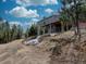 Charming exterior view of a gray mountain home, showcasing its deck, wooded surroundings, and tranquil ambiance at 31932 Steven Way, Conifer, CO 80433