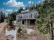 Two-story gray home nestled on a hillside with mature trees and a deck overlooking the natural landscape at 31932 Steven Way, Conifer, CO 80433