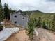 Gray two-story home with snow still on the ground surrounded by the mountain forest on a cloudy day at 31932 Steven Way, Conifer, CO 80433