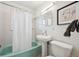 Cozy bathroom with shower-tub combo, pedestal sink, and neutral tile at 1716 Fulton St, Aurora, CO 80010