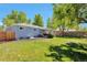 Spacious backyard featuring a lush lawn, mature trees, and a covered patio at 6179 S Bemis St, Littleton, CO 80120