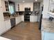 Well-lit kitchen featuring white cabinets, stainless steel appliances, granite countertops, and wood floors at 6179 S Bemis St, Littleton, CO 80120