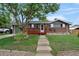 Inviting home featuring a red porch and gray siding, complimented by a well-manicured lawn and a mature tree at 1263 W 103Rd Pl, Northglenn, CO 80260