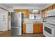 A view of the kitchen featuring wood cabinets, laminate countertops, and stainless steel appliances at 1263 W 103Rd Pl, Northglenn, CO 80260