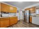An interior kitchen featuring wood cabinets and flooring with white appliances and neutral countertops at 1263 W 103Rd Pl, Northglenn, CO 80260