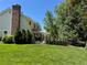 Exterior view of a home with a well-kept yard, mature trees, brick chimney, and covered outdoor patio at 8535 E Otero Cir, Centennial, CO 80112