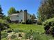 Back exterior with lush plants, covered patio, brick chimney, manicured yard, and mature trees at 8535 E Otero Cir, Centennial, CO 80112