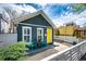 Charming home with a bright yellow door, white fence, and quaint outdoor seating area at 444 Inca St, Denver, CO 80204