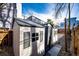 Backyard view of a vinyl storage shed with windows and shutters, accessible via a paved walkway at 444 Inca St, Denver, CO 80204