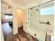 Modern bathroom with glass shower, marble-look tile, wood floors, and view into the bedroom at 21924 E Lake Ave, Aurora, CO 80015