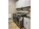 Bright laundry room with modern washer, dryer, and ample white cabinet storage at 4545 Oxbow Dr, Brighton, CO 80601