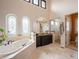 Bright bathroom with soaking tub, decorative windows, and a glass-enclosed shower, offering a spa-like experience at 2117 S Juniper St, Lakewood, CO 80228