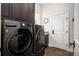 Well-equipped laundry room includes dark cabinets, modern washer and dryer, and decorative wreath at 2117 S Juniper St, Lakewood, CO 80228