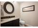 Chic powder room featuring dark cabinets, granite countertop, modern fixtures, and decorative mirror at 2117 S Juniper St, Lakewood, CO 80228