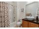 Bathroom featuring a shower over tub, decorative curtain, vessel sink, wood cabinet, and granite countertop at 2670 E 136Th Pl, Thornton, CO 80602