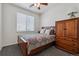 Cozy bedroom with a ceiling fan, window, and bed dressed with a colorful quilt and matching wooden furniture at 2670 E 136Th Pl, Thornton, CO 80602